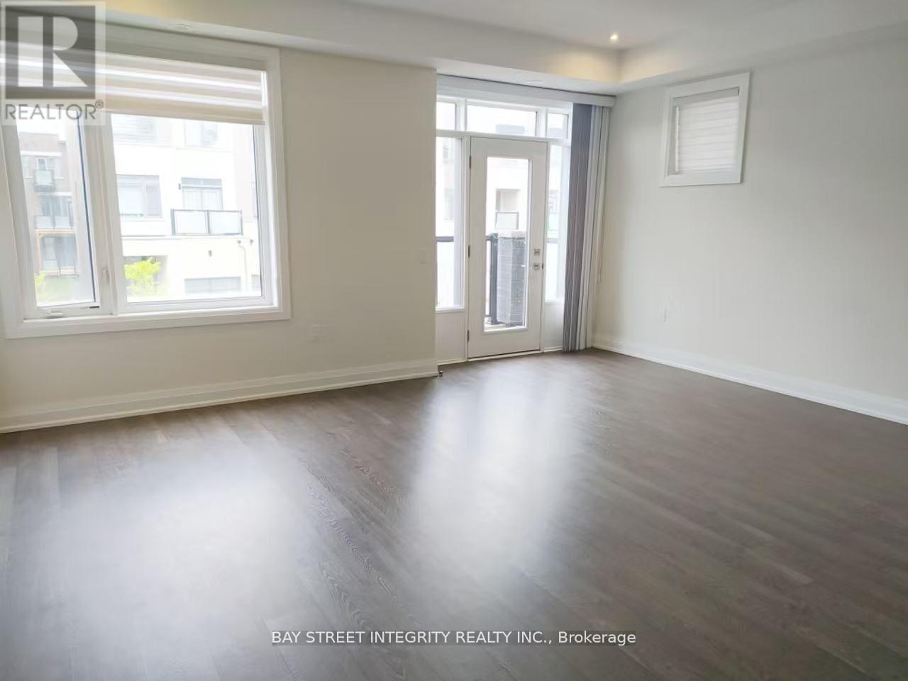A spacious room with wooden flooring and a sliding glass door.