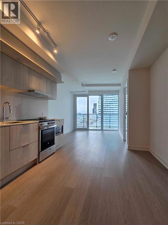 A modern kitchen with wooden floors and stainless steel appliances.