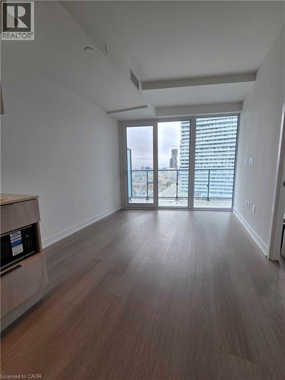 A spacious room with wooden flooring and a sliding glass door leading to a balcony.