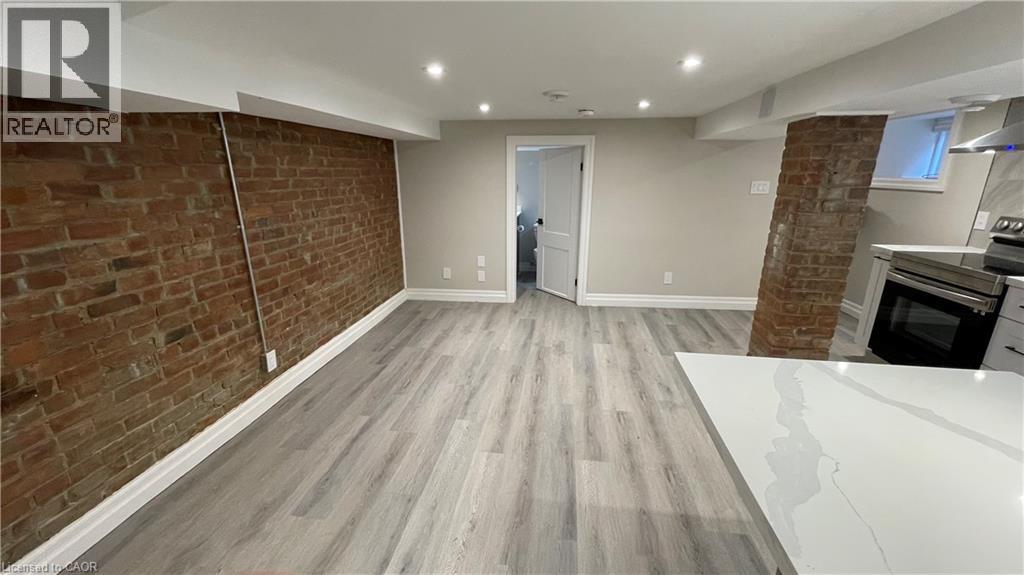 A spacious room with a brick wall and wooden flooring.