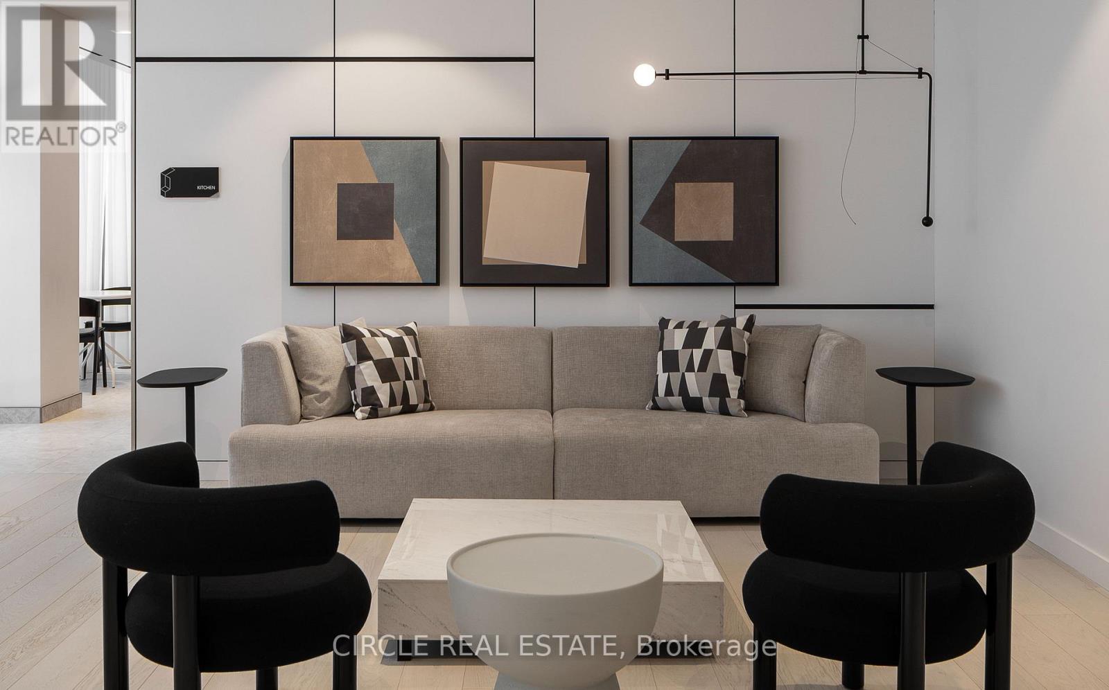 A modern living room with a grey couch, two black chairs and a coffee table.