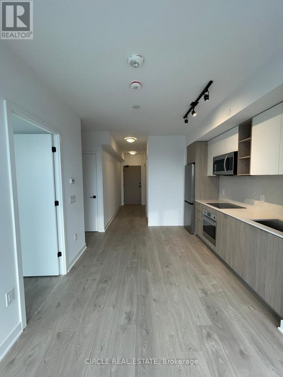 A modern kitchen with white cabinets and a wooden floor.