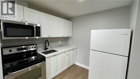 A kitchen with white cabinets and a white fridge.