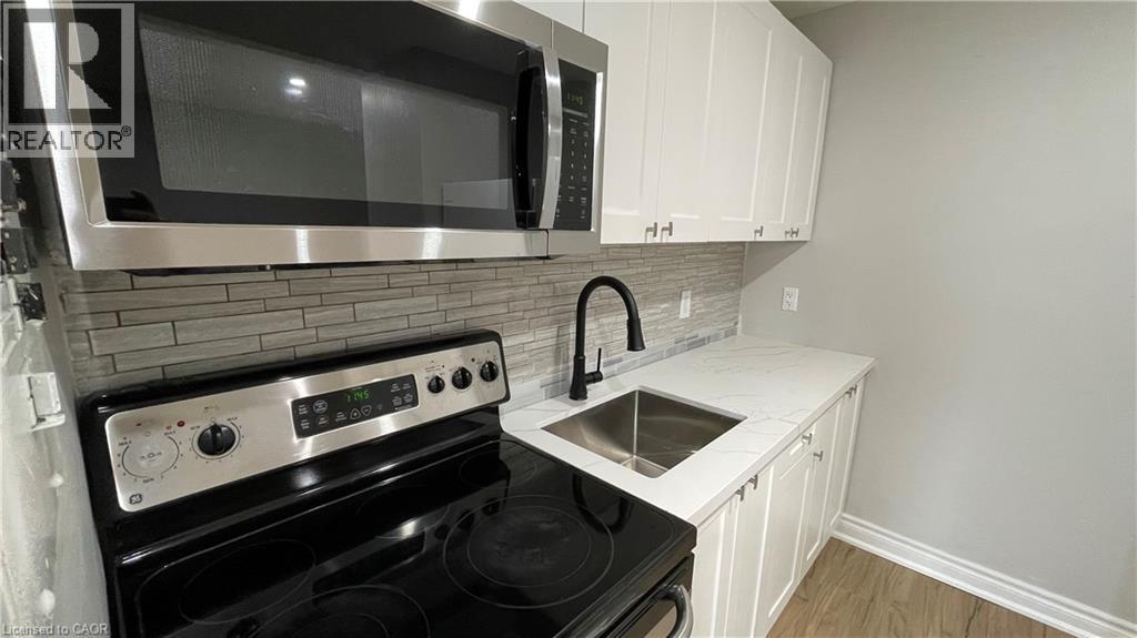 A kitchen with a black stove top oven and a microwave above it.