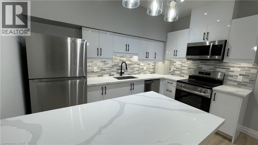 A modern kitchen with a white countertop and stainless steel appliances.