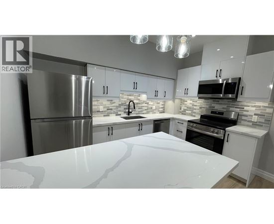 A modern kitchen with a white countertop and stainless steel appliances.