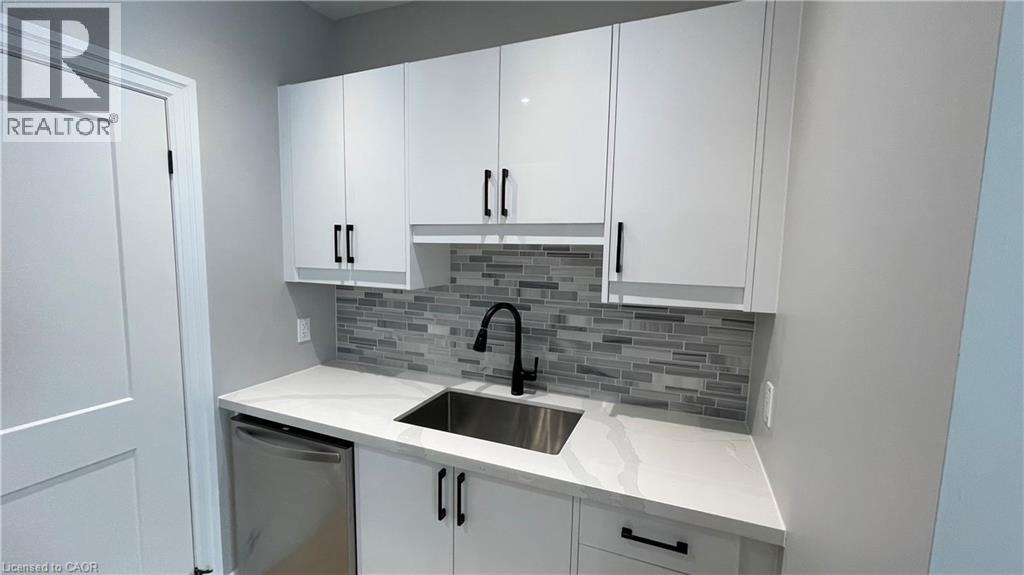A kitchen with white cabinets and a grey backsplash.
