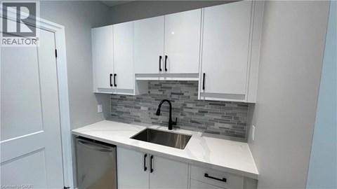 A kitchen with white cabinets and a grey backsplash.