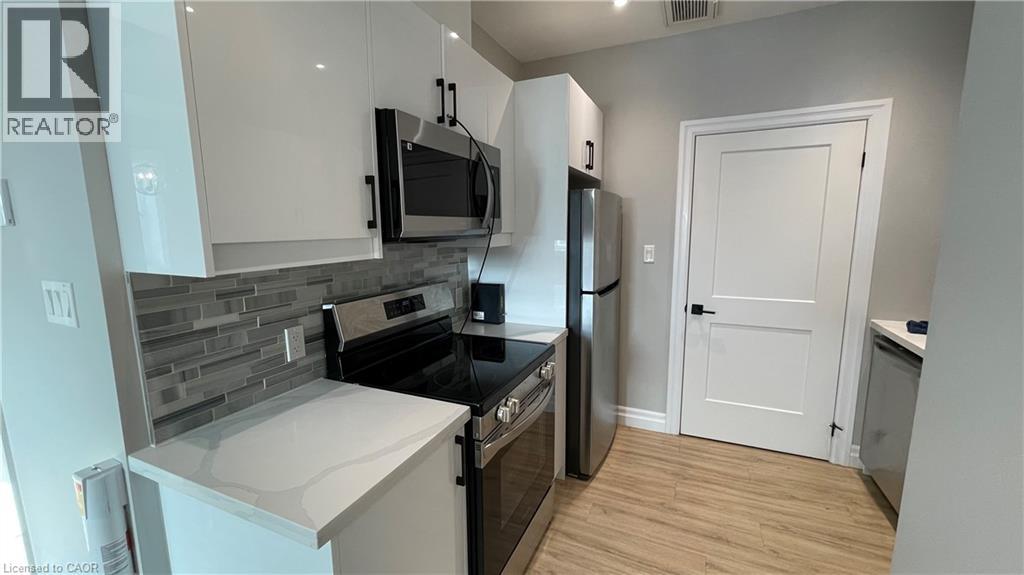 A kitchen with a refrigerator, microwave, and oven.