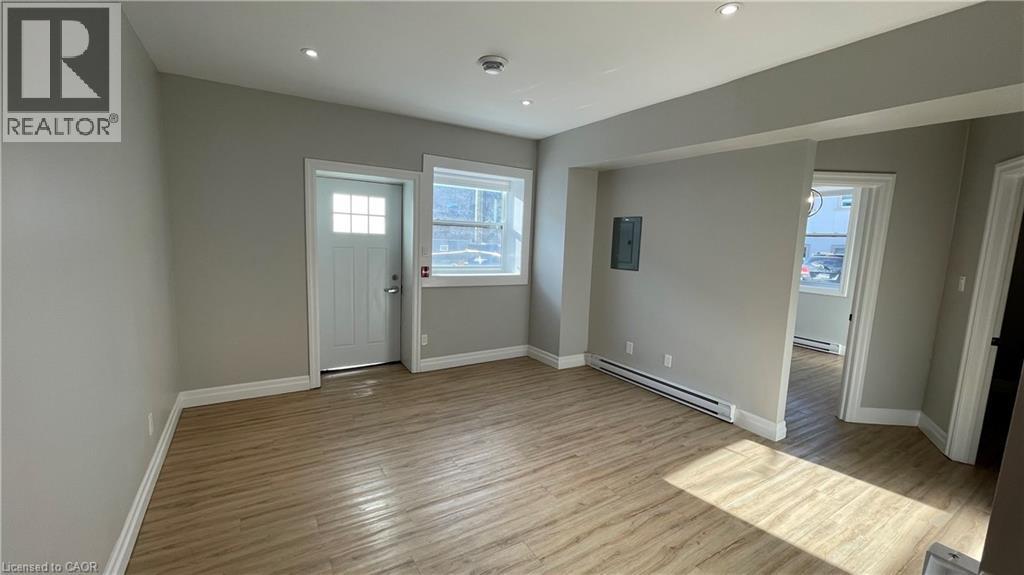 A spacious room with wooden flooring and white walls.