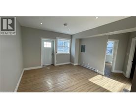 A spacious room with wooden flooring and white walls.