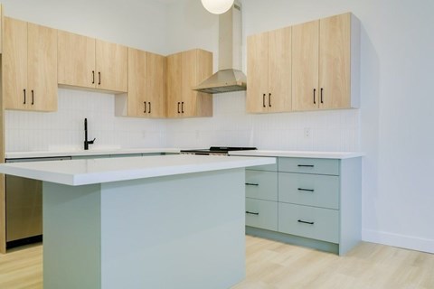 A kitchen with a white countertop and wooden cabinets.