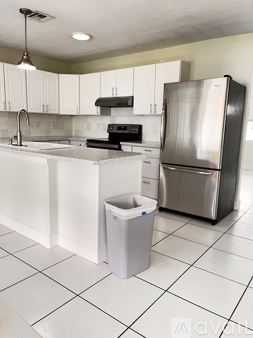 A kitchen with white cabinets and a silver refrigerator.