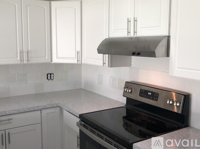 A kitchen with white cabinets and a black stove top oven.