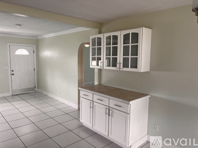 A kitchen with white cabinets and a white door.