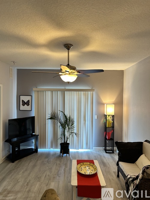 A living room with a television, a couch, and a potted plant.