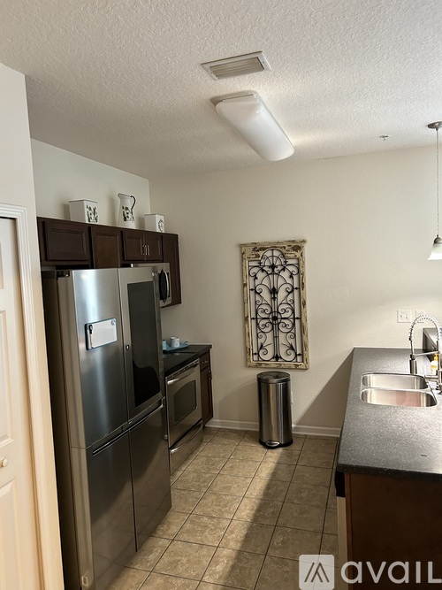 A kitchen with a stainless steel refrigerator and microwave, a sink, and a window with a decorative iron grill.
