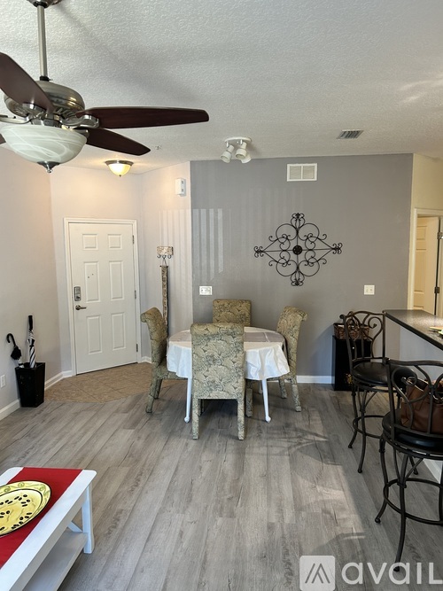 A dining room with a table set for four and a ceiling fan.