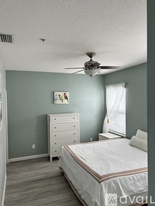 A bedroom with a bed, dresser, and window.