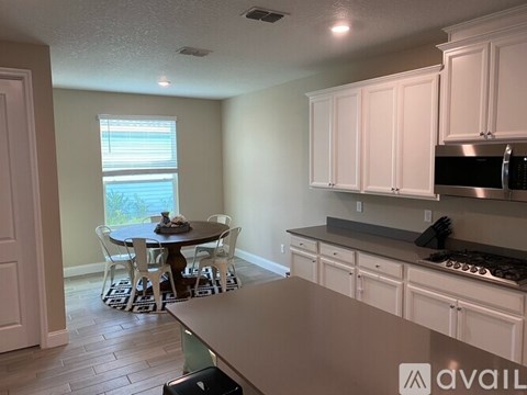 A kitchen with white cabinets and a dining table with chairs.