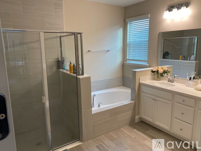 A bathroom with a glass shower door, a bathtub, a sink, and a mirror.