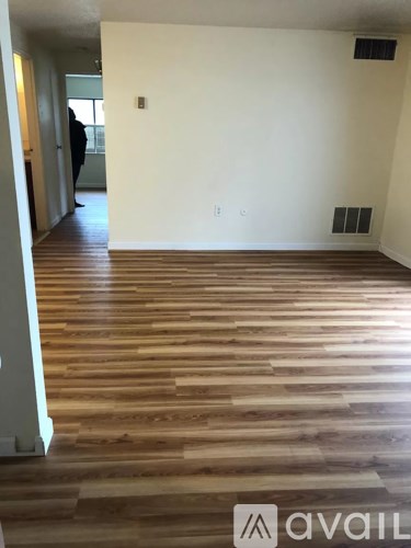 A room with wooden flooring and a person standing in the background.