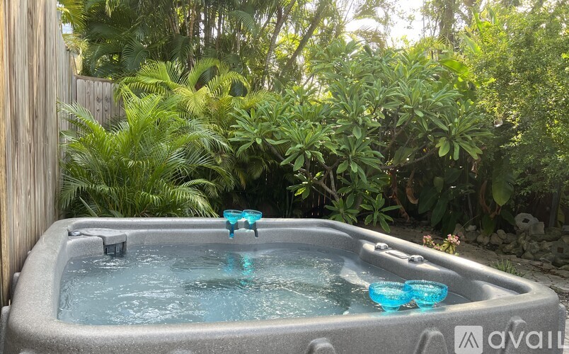 A hot tub with blue floaters is surrounded by greenery.