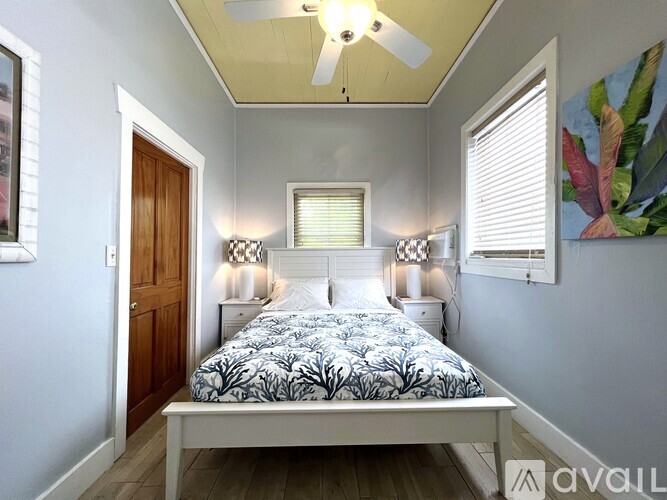 A bedroom with a bed, two lamps, and a painting on the wall.