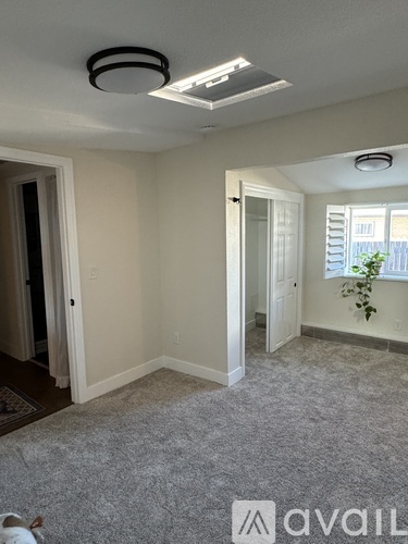 A room with a carpeted floor and a window with blinds.