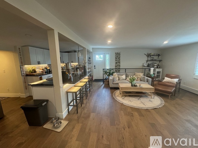 A spacious living room with a kitchen in the background.