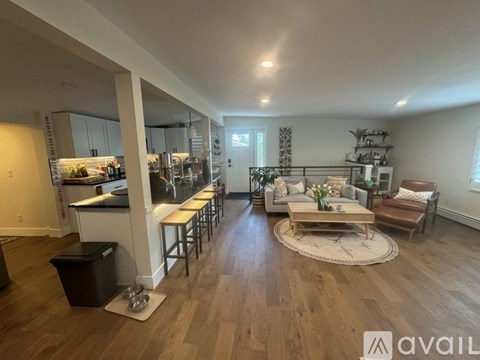 A spacious living room with a kitchen in the background.