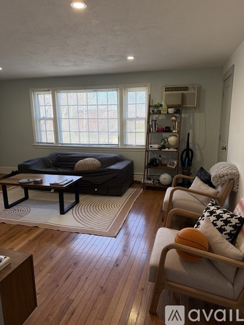 A living room with a black couch and wooden floors.