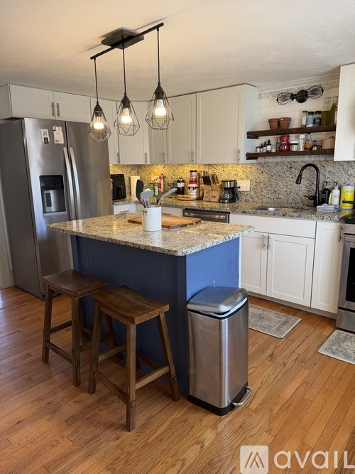 A kitchen with a blue island and wooden stools.