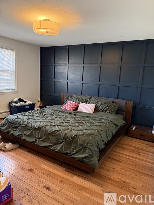 A bedroom with a bed, pillows, and a wooden floor.