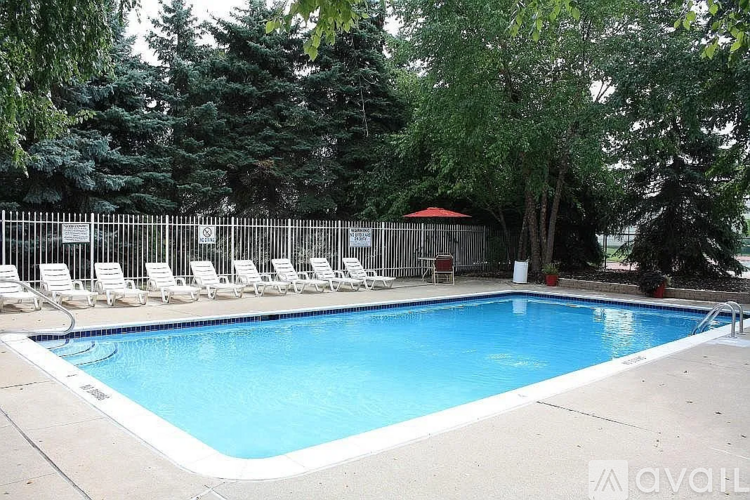 A pool surrounded by trees and lounge chairs.