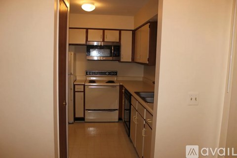 A kitchen with white appliances and wooden cabinets.
