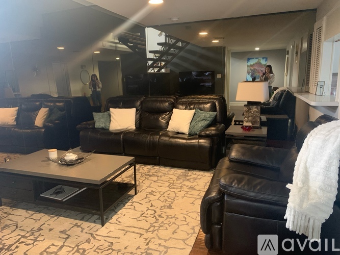 A living room with black leather furniture and a patterned carpet.