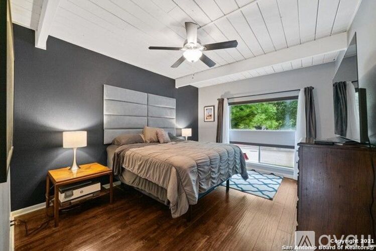 A bedroom with a bed, nightstand, and window.