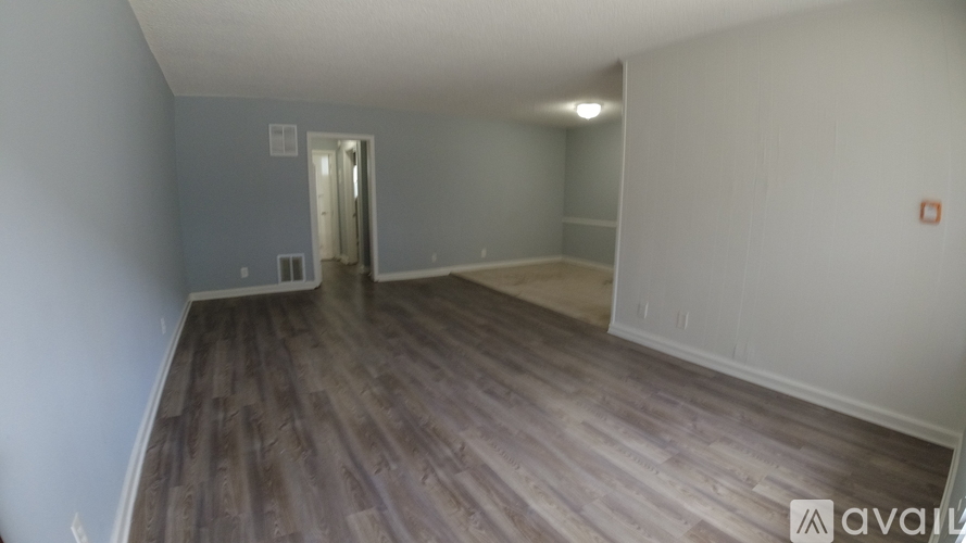 A room with wooden flooring and a doorway leading to another room.
