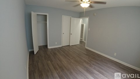 A room with a ceiling fan and wood flooring.