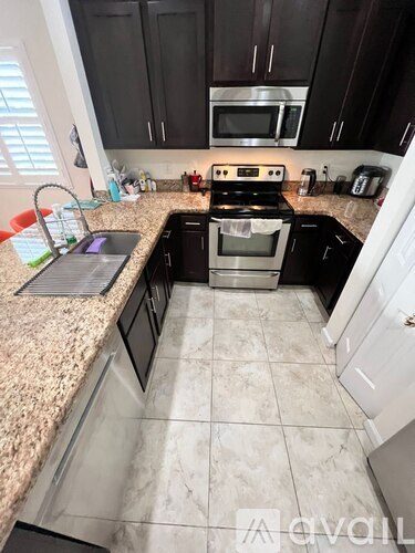 A kitchen with black cabinets and a granite countertop.