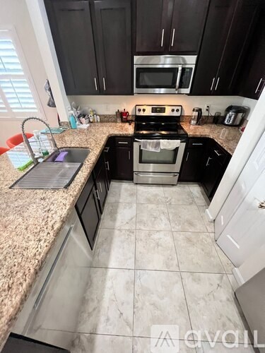 A kitchen with black cabinets and a granite countertop.