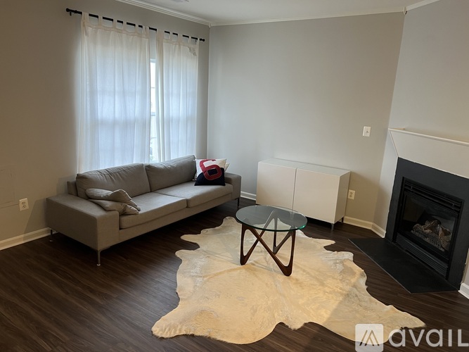 A living room with a grey couch, a glass coffee table, and a cowhide rug.