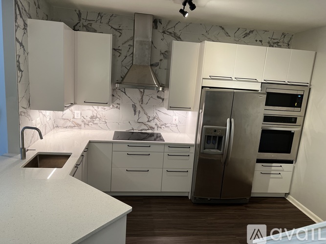 A kitchen with white cabinets and a marble backsplash.