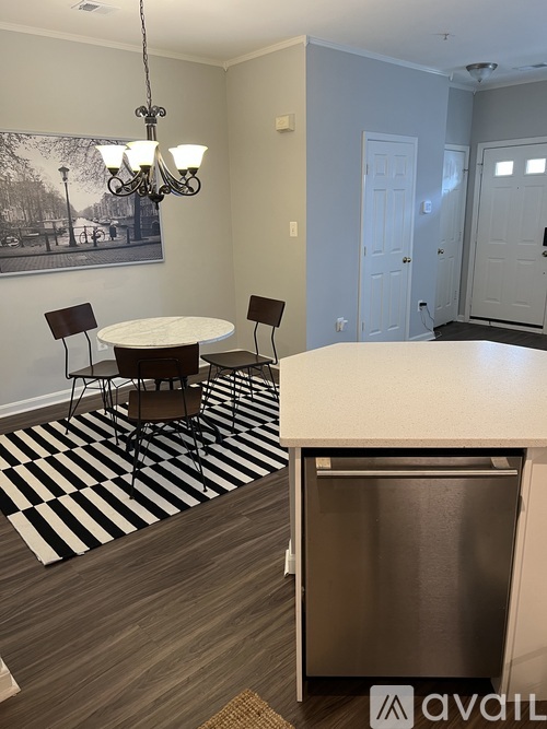A dining room with a table and chairs and a framed picture on the wall.