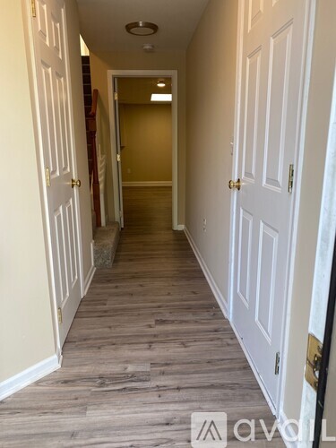 A hallway with white doors and wooden floors.