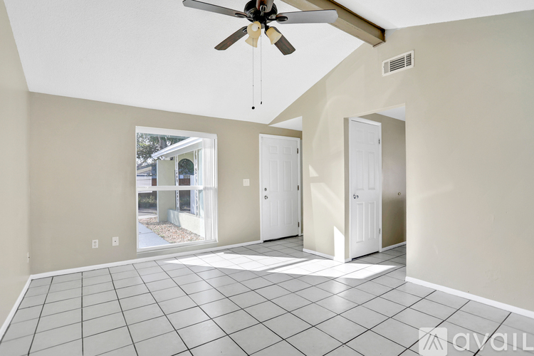 A room with a ceiling fan and tile flooring.