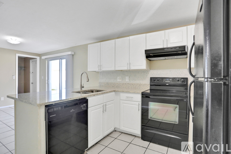 A kitchen with black appliances and white cabinets.