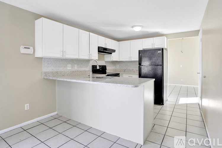 A kitchen with white cabinets and a black refrigerator.