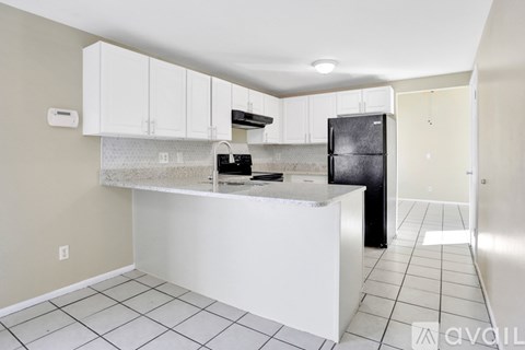A kitchen with white cabinets and a black refrigerator.